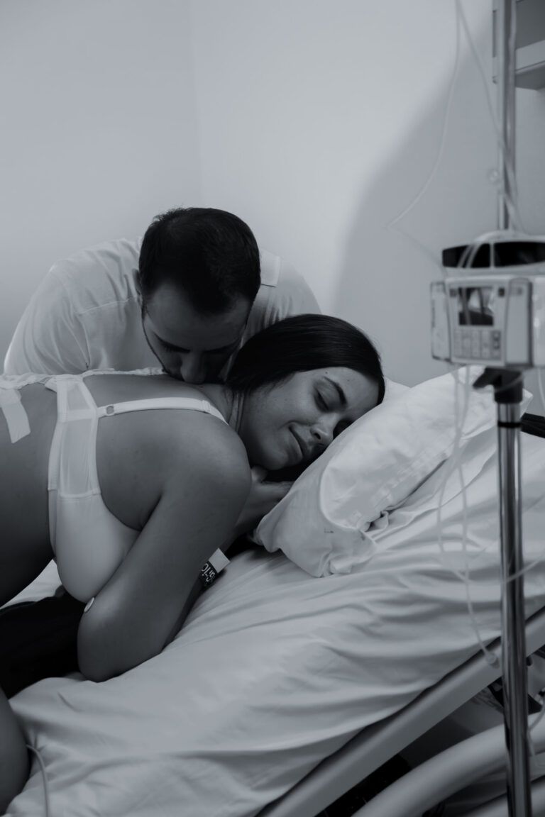 Padre besando a la madre en la cama del hospital tras el parto