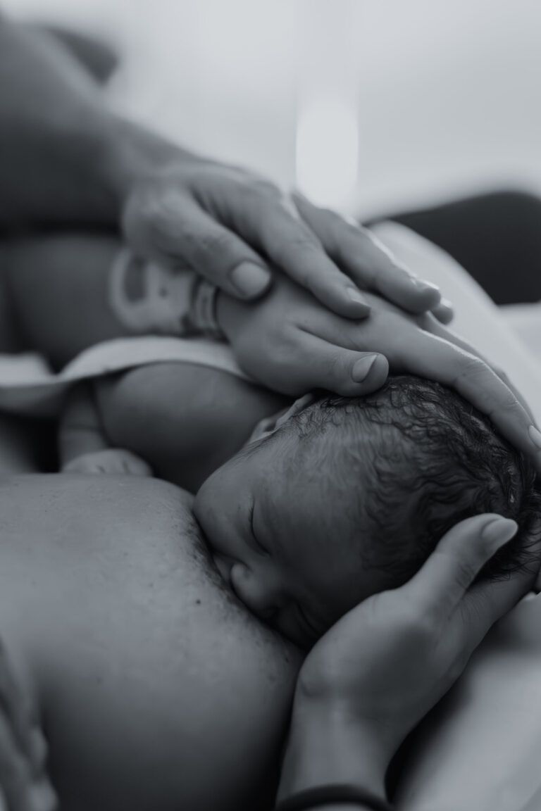 Manos de la madre sobre su bebé recién nacido, en blanco y negro