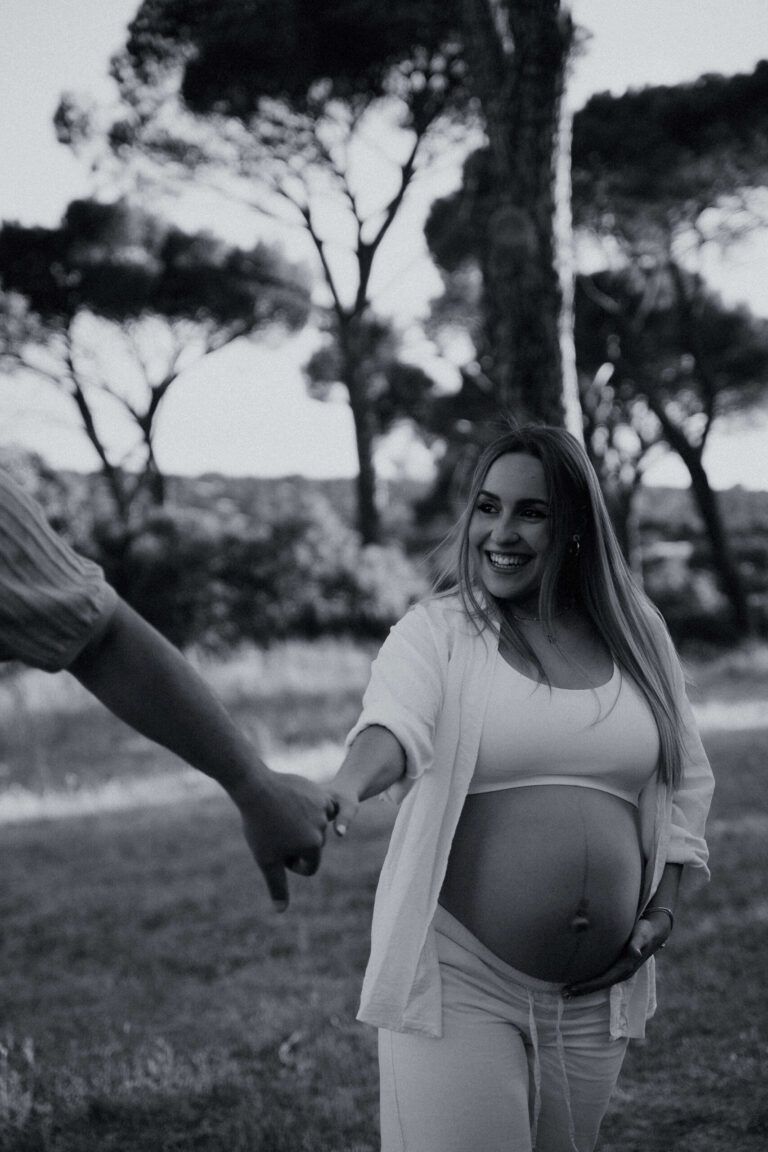 Embarazada sonriendo de la mano de su pareja en el campo, en Madrid