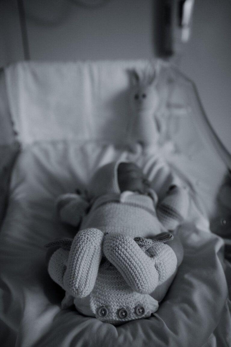Bebé recién nacido con un muñeco de punto, en blanco y negro